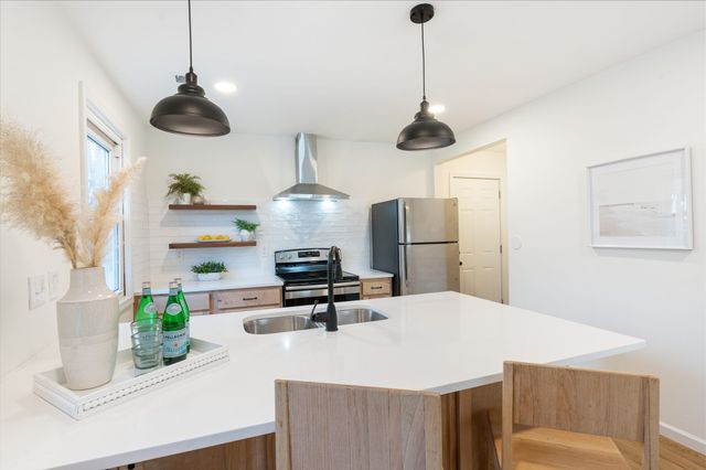 a kitchen with stainless steel appliances granite countertop a sink a refrigerator a stove and a wooden floor