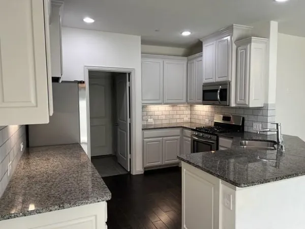 a kitchen with kitchen island granite countertop stainless steel appliances a stove a sink a refrigerator a microwave and cabinets