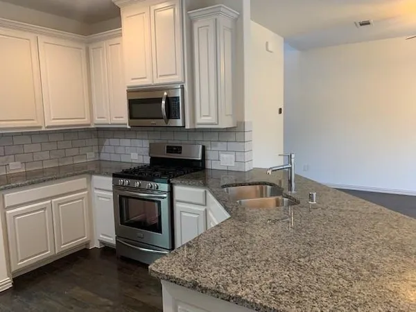 a kitchen with granite countertop a sink stainless steel appliances and cabinets