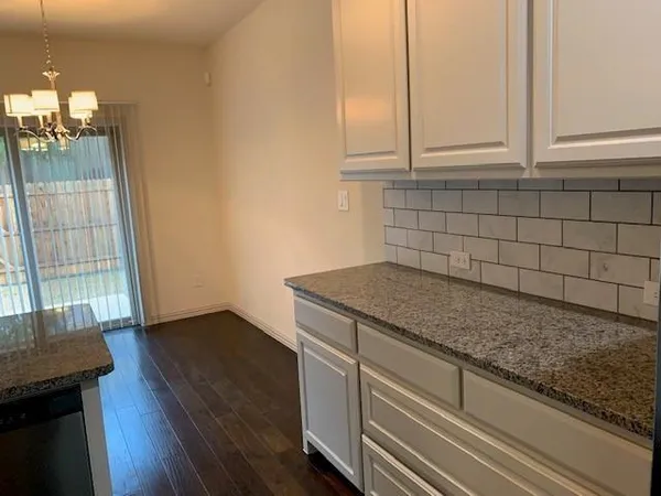 a kitchen with granite countertop white cabinets and a wooden floor