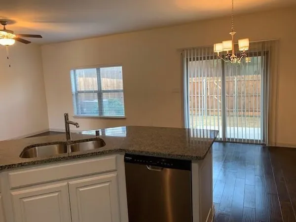 a kitchen with granite countertop a sink and a white wooden cabinets