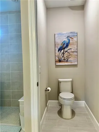 a bathroom with a toilet and a painting on the wall
