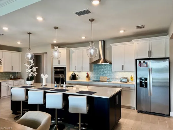 a kitchen with cabinets a sink appliances and chairs