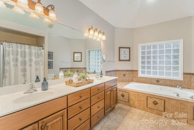 a spacious bathroom with double vanity sinks a large mirror and a bathtub