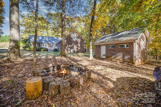 a backyard of a house with large trees and outdoor seating