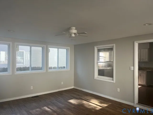 a view of an empty room with a window and wooden floor