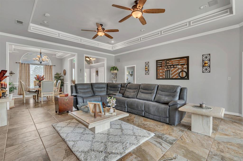 50 Buckingham Lane Allen, TX 75002 - Photo 15 of 39 Living room featuring a raised ceiling, ornamental molding, a ceiling fan, and a chandelier