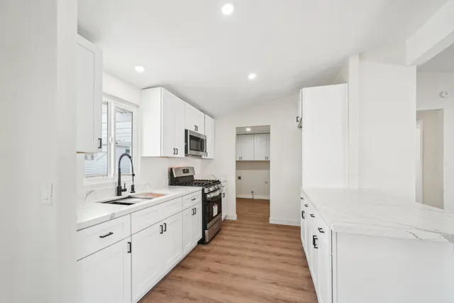 a kitchen with stainless steel appliances a sink dishwasher a stove and a microwave oven with wooden floor