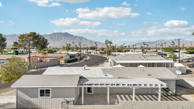 a view of a white house next to a yard with big trees
