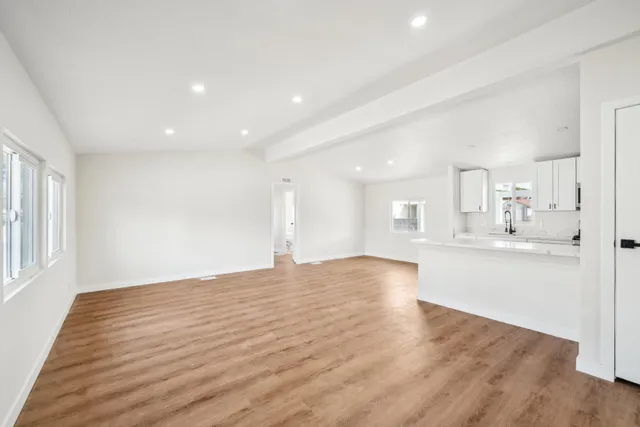 a view of an empty room with window and wooden floor