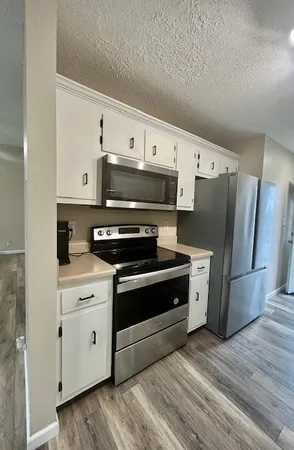 a kitchen with stainless steel appliances a refrigerator stove and white cabinets