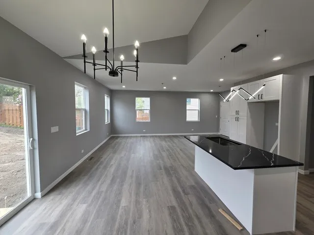 a kitchen with granite countertop a stove a sink a refrigerator and wooden floor