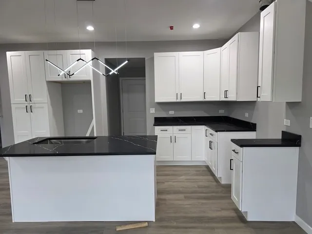 a kitchen with stainless steel appliances granite countertop a stove a sink and white cabinets