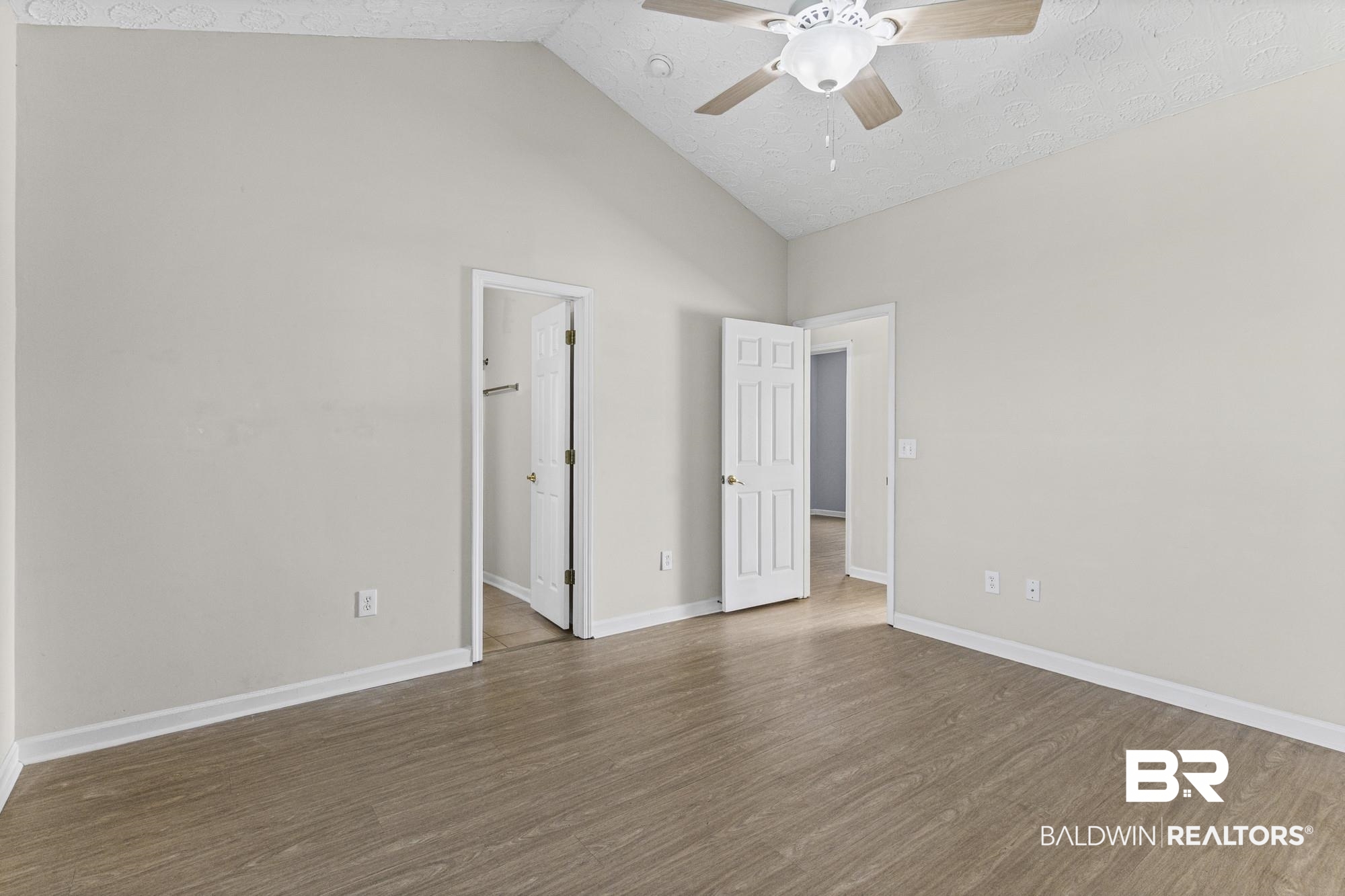 1153 Sloane Cove Foley, AL 36535 - Photo 17 of 25 Unfurnished bedroom with a high textured ceiling, a ceiling fan, dark wood-style flooring, and a walk in closet