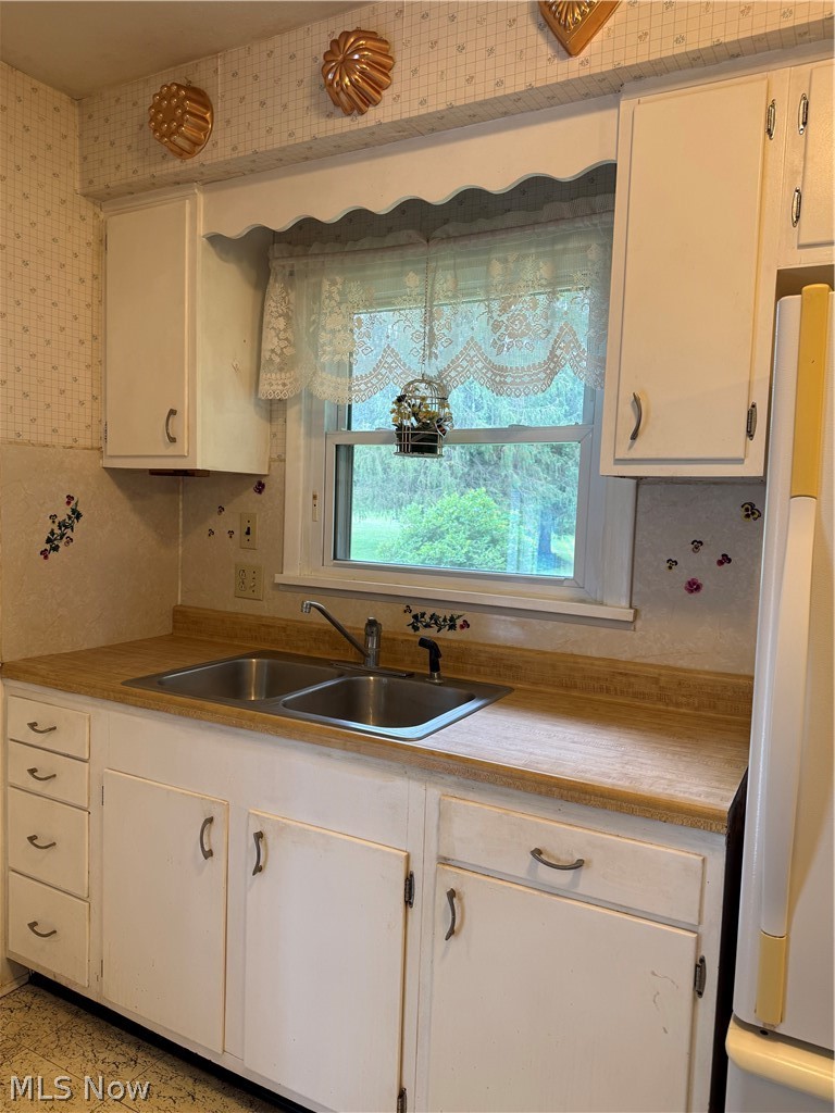 10993 Claridon Troy Road Chardon, OH 44024 - Photo 3 of 20 Kitchen featuring a double basin stainless steel sink, wood-finish countertops, white cabinetry with curved hardware, and a window with a valance