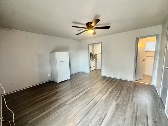 an empty room with wooden floor closet and windows