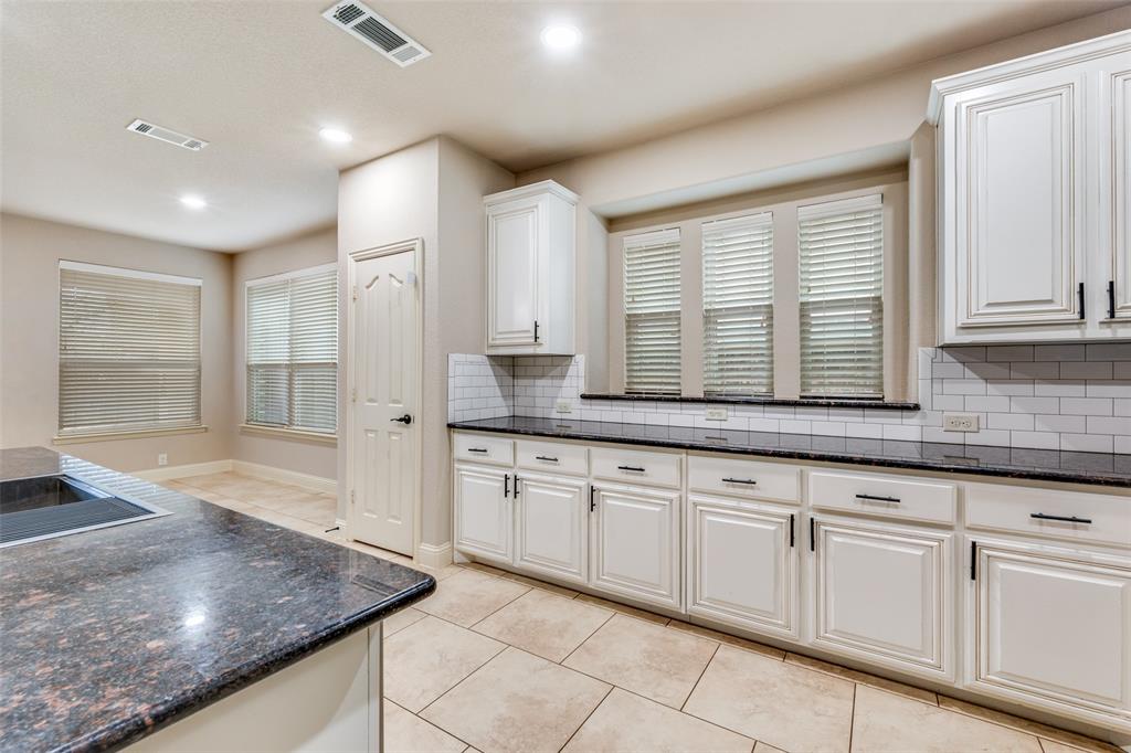 1137 Cardinal Ridge Road Burleson, TX 76028 - Photo 12 of 28 a large kitchen with granite countertop a sink and white cabinets