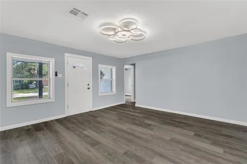 a view of an empty room with wooden floor and a window