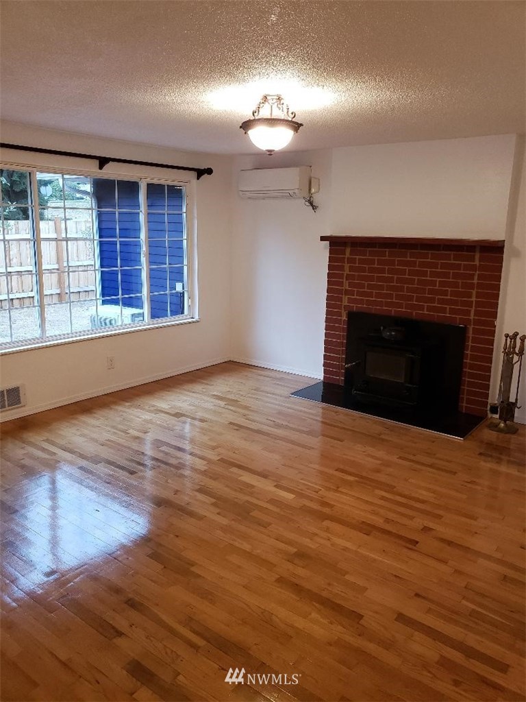 217 228th Street Southeast Bothell, WA 98021 - Photo 14 of 20 an empty room with wooden floor fireplace and windows