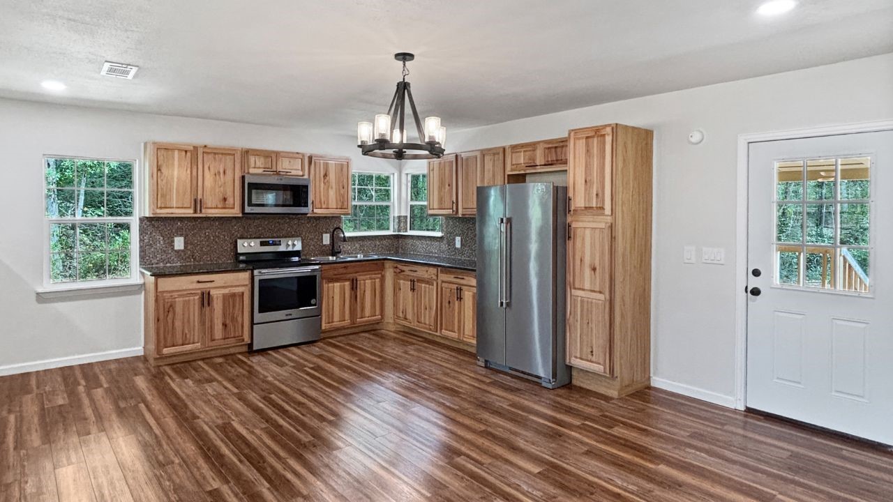 5680 Fm 252 Jasper, TX 75951 - Photo 6 of 23 a kitchen with stainless steel appliances granite countertop a refrigerator a stove top oven a sink dishwasher and wooden floor