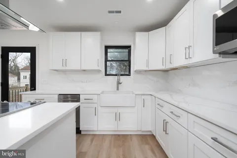 a kitchen with white cabinets appliances and a sink