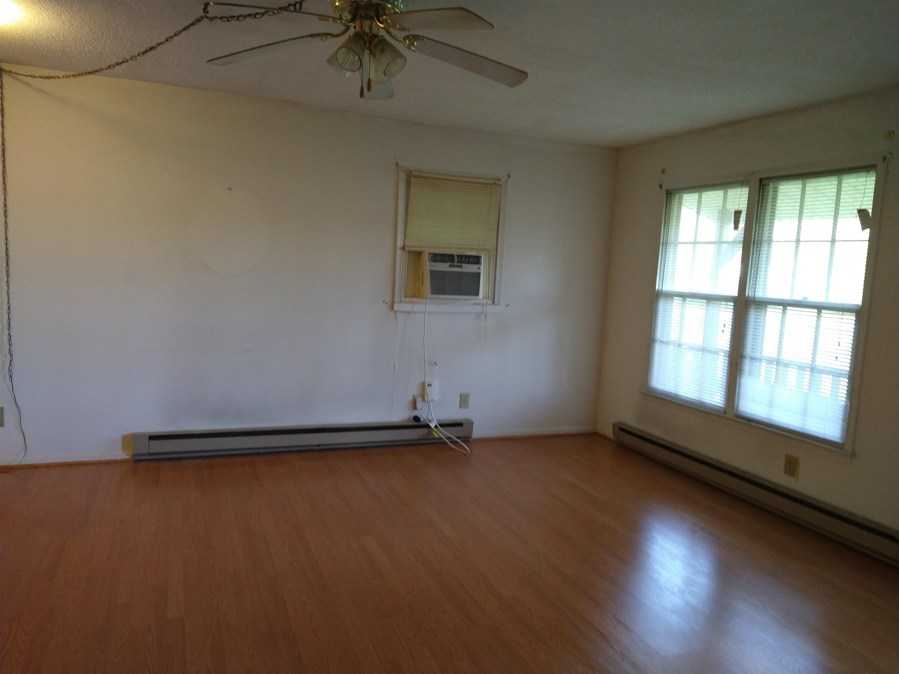 381 Friendship Church Road Middlesex, NC 27557 - Photo 8 of 19 an empty room with wooden floor and windows with curtains