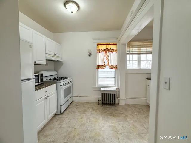 a kitchen with granite countertop a sink cabinets and stainless steel appliances