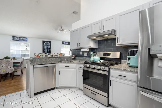 a kitchen with stainless steel appliances granite countertop a stove a sink and a refrigerator