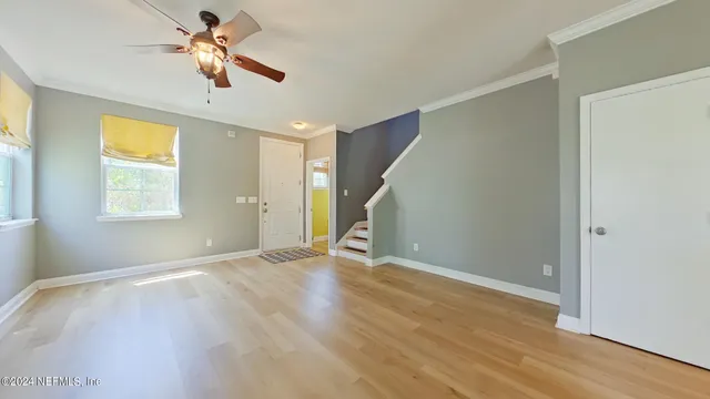 a view of empty room with wooden floor and fan