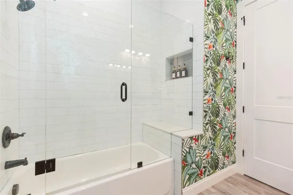 a kitchen with stainless steel appliances kitchen island granite countertop a refrigerator a sink a stove and white cabinets with wooden floor