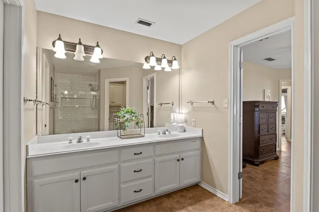 a spacious bathroom with a granite countertop sink a mirror and a shower