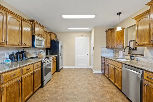 a large kitchen with stainless steel appliances granite countertop a stove a sink dishwasher and a refrigerator