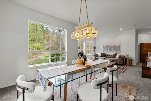 a view of a dining room with furniture a chandelier and large windows