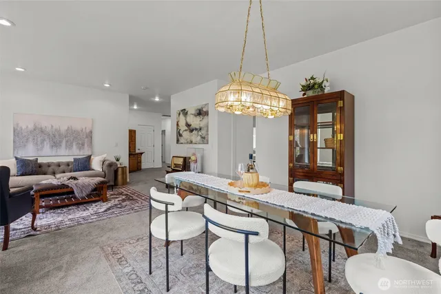 a living room with dining table and a chandelier