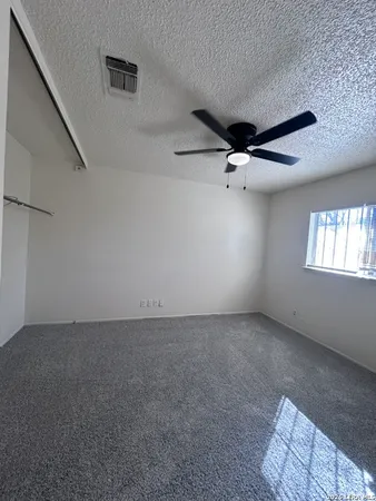 an empty room with windows and ceiling fan