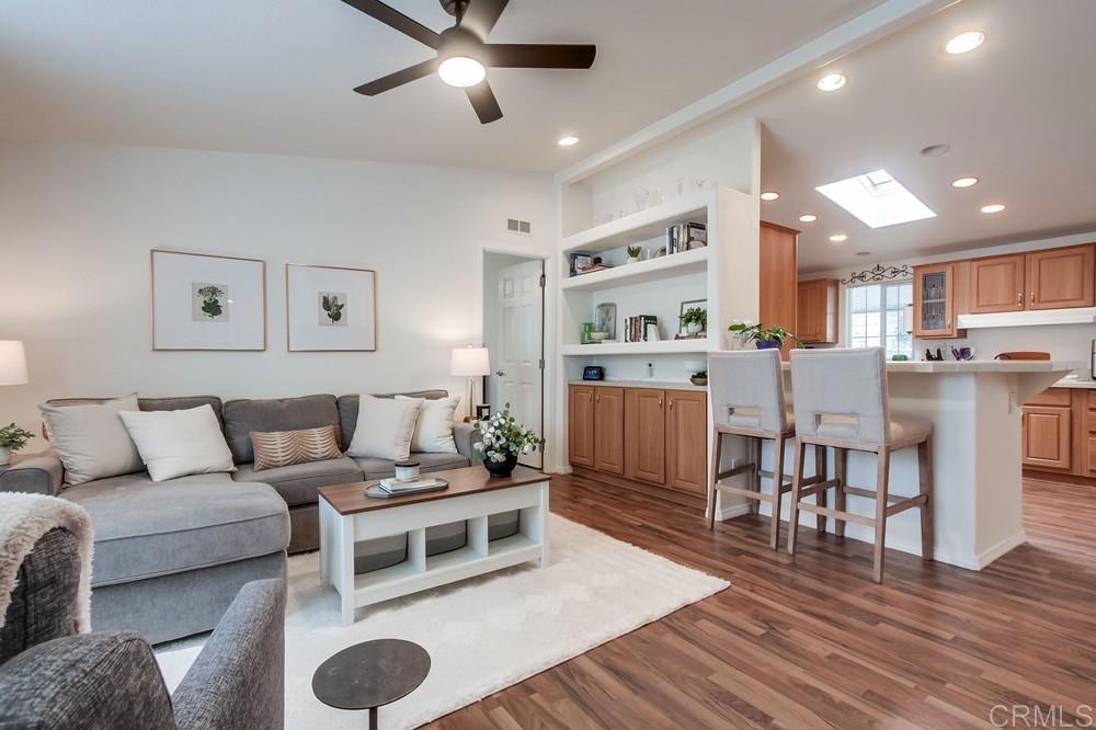 a living room with stainless steel appliances furniture and a wooden floor