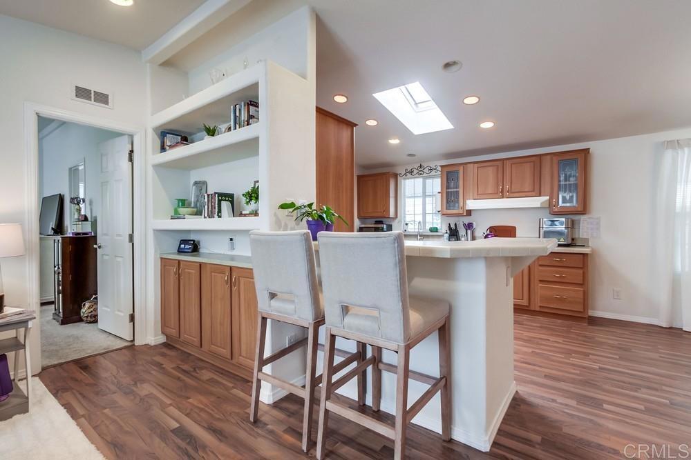 120 Brookside Lane Oceanside, CA 92056 - Photo 12 of 55 a kitchen with stainless steel appliances granite countertop a refrigerator a stove top oven and a dining table with wooden floor