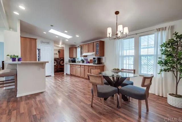 a living room with stainless steel appliances furniture a rug kitchen view and a chandelier