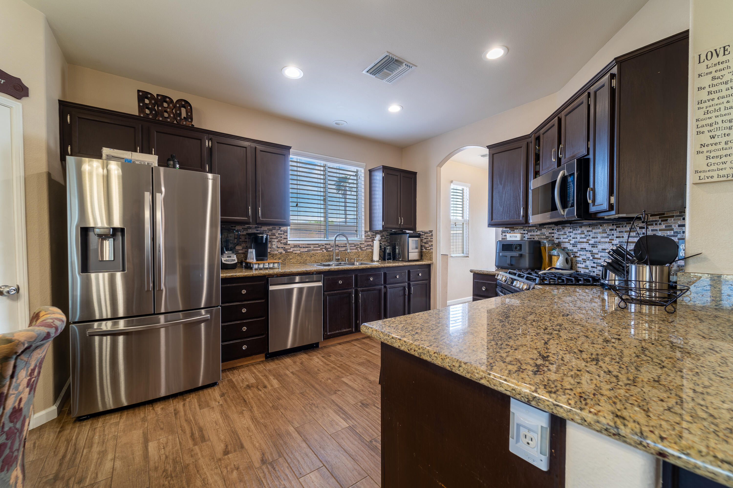 47970 Austin Drive Indio, CA 92201 - Photo 8 of 32 a kitchen with stainless steel appliances granite countertop a refrigerator a sink dishwasher a oven with wooden cabinets and wooden floor