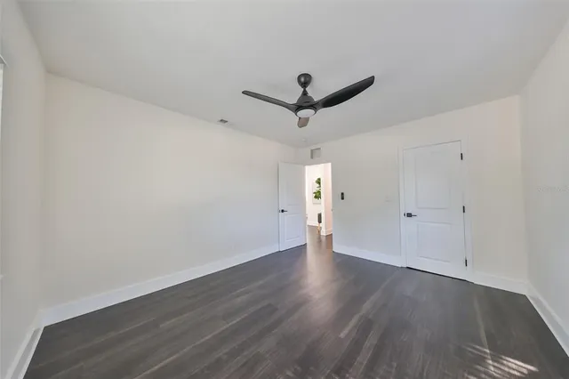 an empty room with wooden floor and a ceiling fan