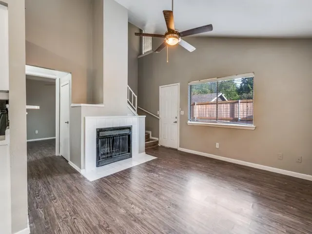 an empty room with wooden floor a fireplace and windows