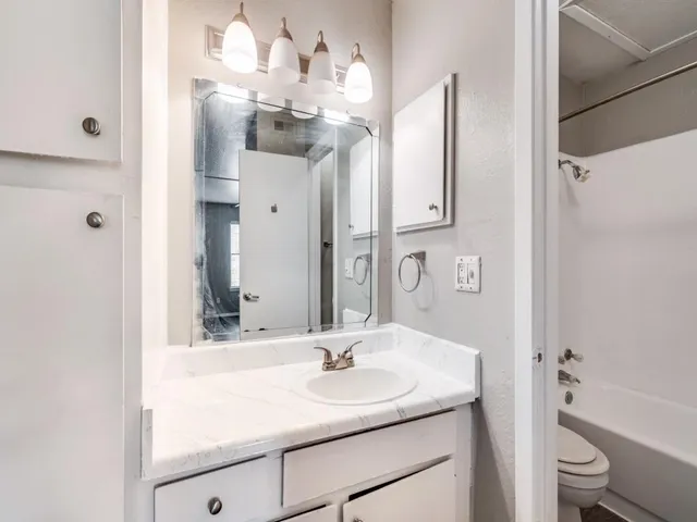 a bathroom with a sink vanity granite tub and a mirror