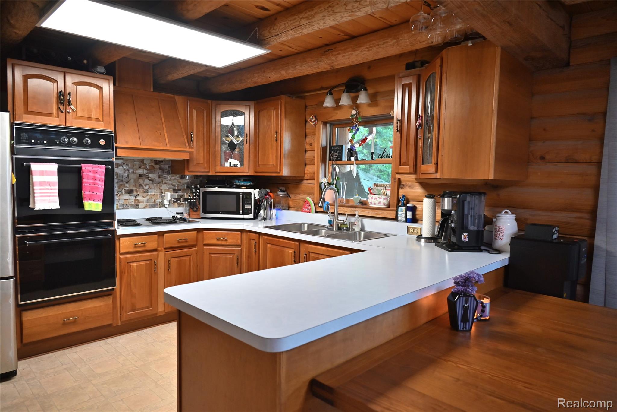 16501 Hannan Road Romulus, MI 48174 - Photo 5 of 20 Kitchen featuring wood cabinetry, white countertops, built-in double ovens, and a natural log wall finish