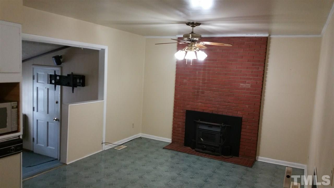 716 Cooper Road Raleigh, NC 27610 - Photo 6 of 25 an empty room with a fireplace and chandelier fan