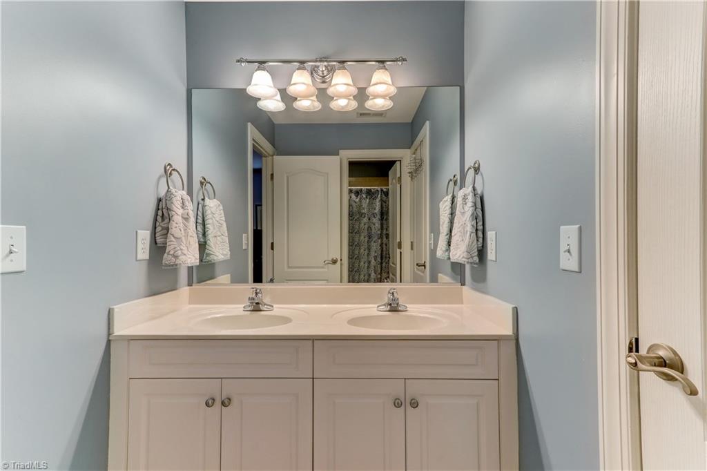 5501 Gray Leigh Drive Oak Ridge, NC 27310 - Photo 20 of 30 Jack and Jill bath attaches to Bedroom 4 and the Hallway. Tile flooring, dual sink vanity with sconce lighting. Separate room with commode and bath/shower combination. Ceramic tub with tile surround.