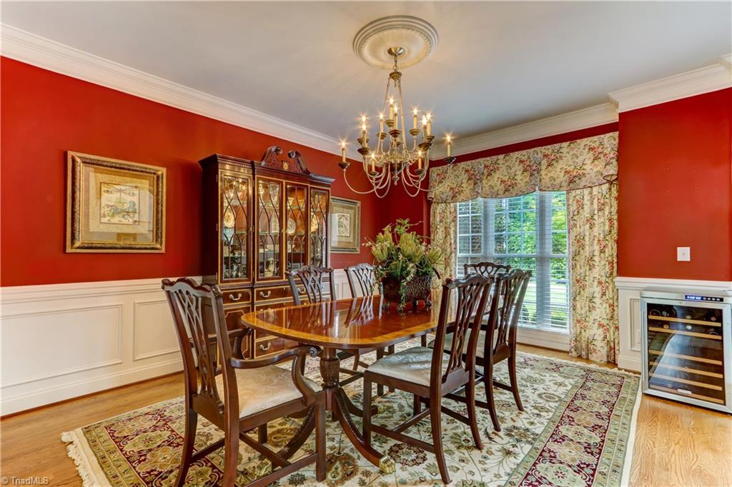 5501 Gray Leigh Drive Oak Ridge, NC 27310 - Photo 5 of 30 The Dining Room features hardwood flooring, paneled wainscoting, and crown molding. Large windows overlook the front yard and have wood blinds. Chandelier not included.