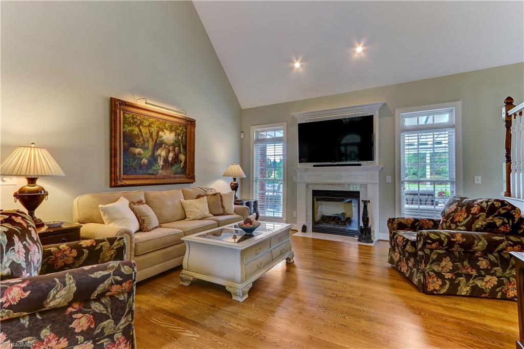 5501 Gray Leigh Drive Oak Ridge, NC 27310 - Photo 6 of 30 The Great Room has a vaulted ceiling, hardwood flooring, gas log fireplace with marble surround & hearth, and wood mantel. Over-sized windows with transom look onto back deck and have wood blinds.