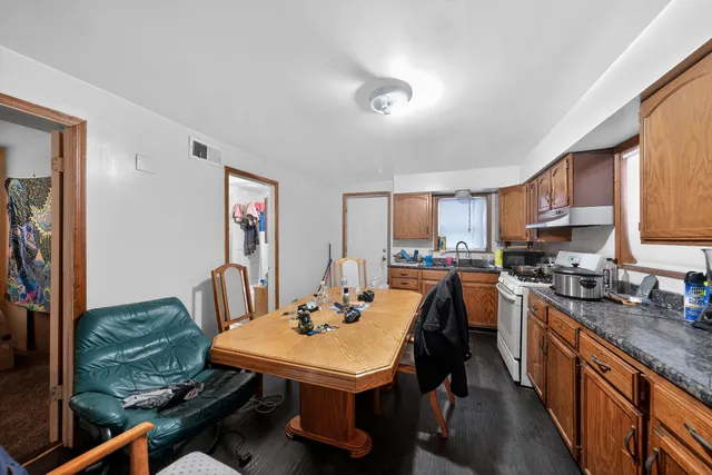 a kitchen with a stove a refrigerator a sink dishwasher with a dining table and chairs