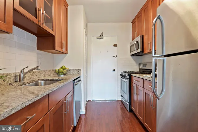 a kitchen with granite countertop a sink a stove and refrigerator