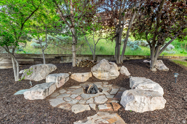 577 South Ridge Top Lane East North Salt Lake, UT 84054 - Photo 52 of 57 Gather around the custom stone fire pit nestled beneath mature trees—an inviting space for relaxing evenings and entertaining family and friends.